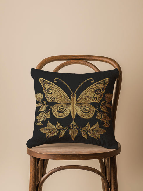 A black woven throw pillow featuring an embroidered gold Hamsa hand surrounded by intricate floral and botanical designs.